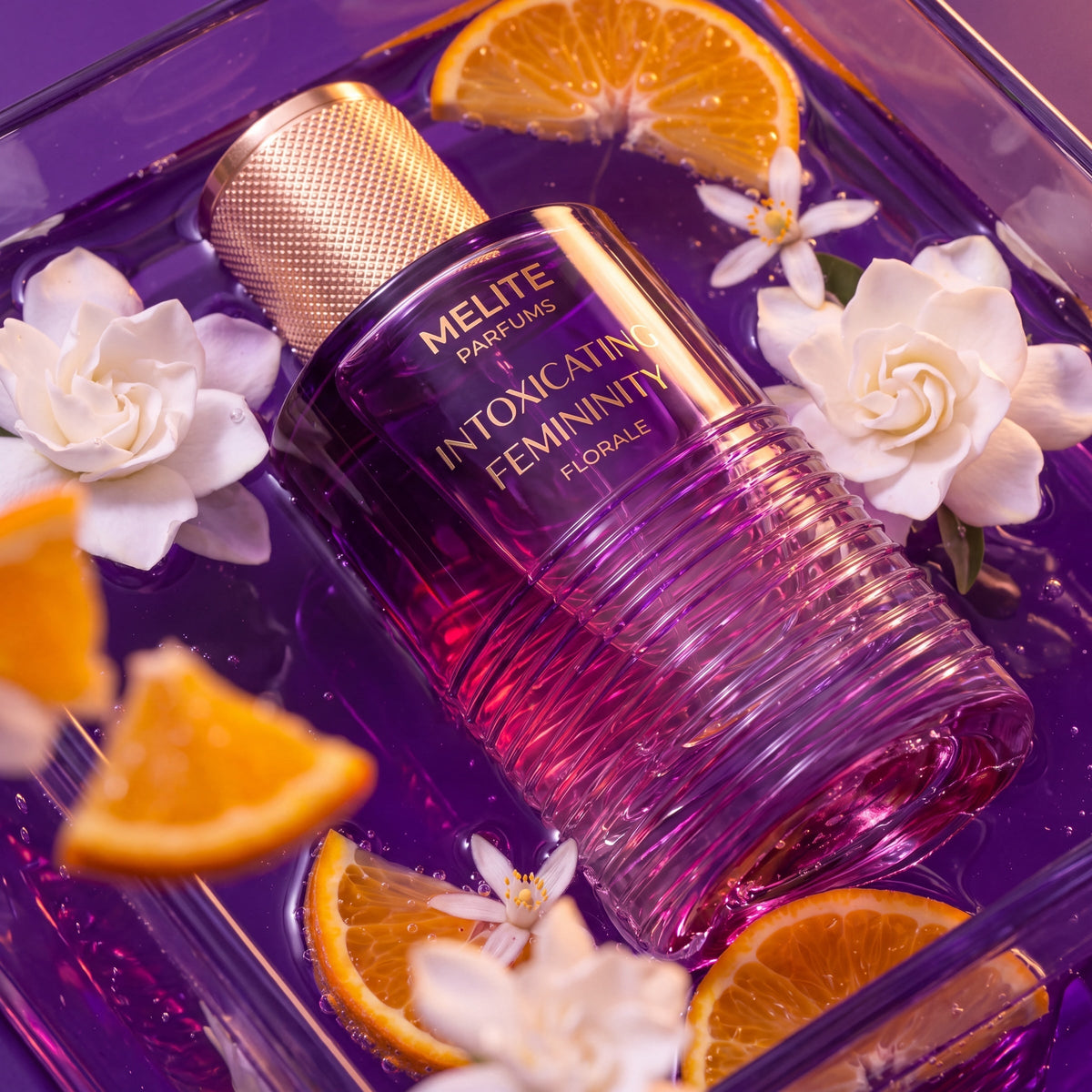 MELITE PARFUMS Intoxicating Femininity Florale perfume bottle in purple water with gardenia flowers and orange slices